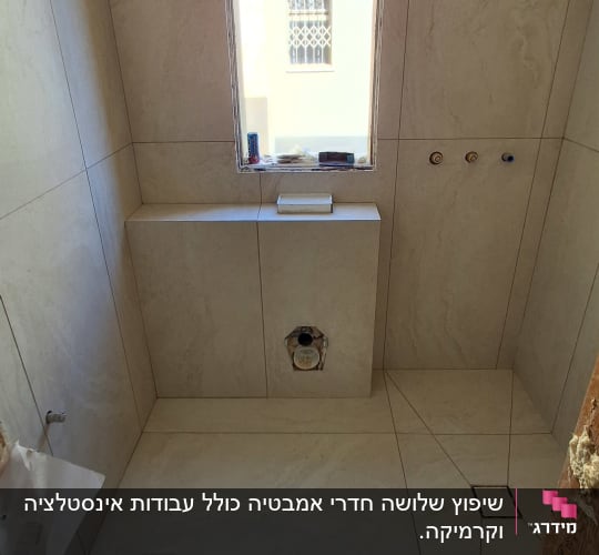 חדר אמבטיה בשיפוץ עם אריחים חדשים וקיר חשוף